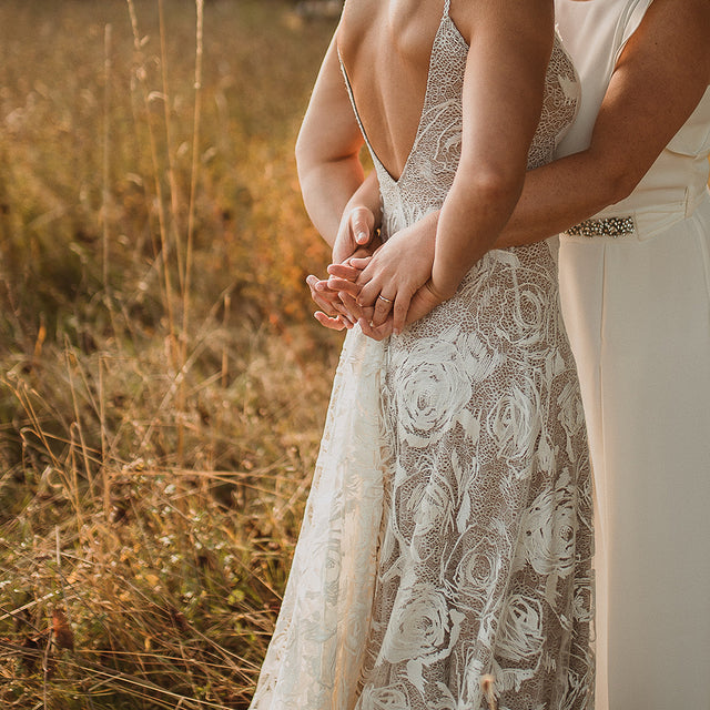 A lesbian couple on their wedding day holding hands and wearing their wedding rings